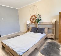 A bedroom in a family house with a bed, a cabinet, and a floor with a wooden decor.
