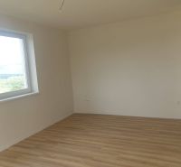 A room in a one-room apartment with white walls and a wooden decor floor.