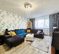 Living room with a bold wallpaper, comfortable sofa, and wooden decor flooring.