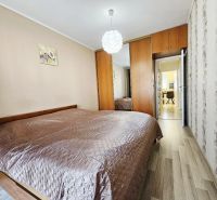 Bedroom with a double bed and built-in wardrobe in a 3-room apartment. Floor with wood decor.