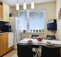 Dining room in a three-room apartment with a wooden decor floor, complemented by modern lighting.