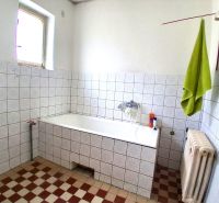 Bathroom in a family house with white tiles and a bathtub.
