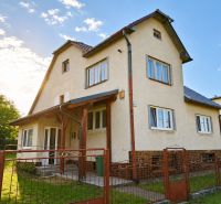 A family house in Sebechleby with a fence and a landscaped garden under a blue sky.