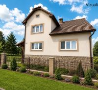 A family house in Sebechleby surrounded by a landscaped garden and a fence under a blue sky.