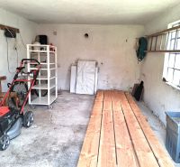 A garage in a family house with tools and a lawnmower on a concrete floor.