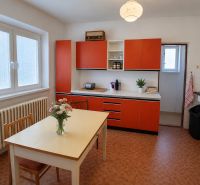 A kitchen in a family house with red cabinets and a table with flowers.