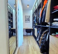 A narrow wardrobe room in a 3-room apartment with a wooden decor floor and shelves.