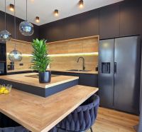 A kitchen in a 3-room apartment with black cabinets and a wooden decor floor.