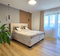 Bedroom in a 3-room apartment with a bed, a plant, and a wooden decor floor.