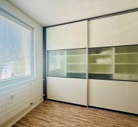 A room with a sliding wardrobe and a floor with a wooden decor in a 3-room apartment.