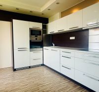 A kitchen in a 3-room apartment with a wooden decor floor and built-in appliances.