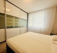 A bright bedroom with a large built-in wardrobe in a 3-room apartment and a floor with a wooden decor.