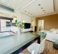 Living room with kitchen in a three-room apartment with a wooden decor floor.
