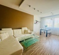 Living room in a 3-room apartment with a wood-patterned floor and modern furniture.
