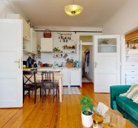 A kitchen with a dining table, a green sofa, and a wooden decor floor in a 3-room apartment.
