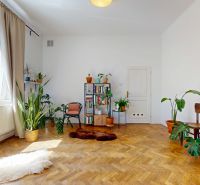A bright living room space in a 3-room apartment with wooden decor and plants.