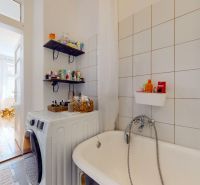 A bathroom with a bathtub, a washing machine, and a shelf for cosmetics in a 3-room apartment.