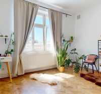 Bright living room in a 3-room apartment with plants, a bookshelf, and a table, wooden decor flooring.