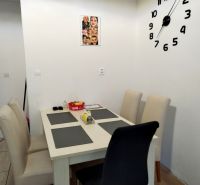 Dining area with four chairs and a large clock on the wall in a 2-room apartment.