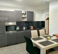 A kitchen in a 2-room apartment with dark gray cabinets and a white table.