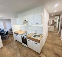 A kitchen in a 2-room apartment with tiles and a wooden decor on the cabinets.