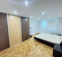 A bedroom with a wood-patterned floor and a large built-in wardrobe in a 2-room apartment.