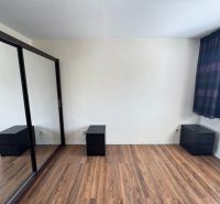 Interior of a 3-room apartment with a wooden decor floor, wardrobes, and nightstands.
