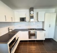 A kitchen in a 3-room apartment with white cabinets and a dark countertop.