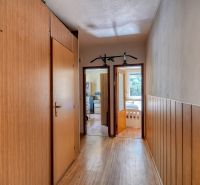 A hallway with walls featuring a wooden decor in a 4-room apartment, with visible doors to the rooms.