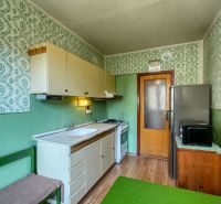 Kitchen of a 4-room apartment with wallpaper, wood-patterned flooring, and basic equipment.