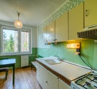 A kitchen in a 4-room apartment with a wooden decor floor and green walls.