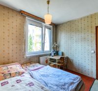 Bedroom in a 4-room apartment with a bed, table, wallpaper, and doors with a wooden decor.