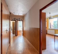 A hallway with a wooden decor floor in a 4-room apartment with entrances to the rooms.