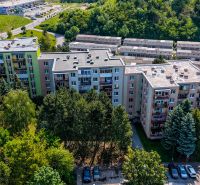 A view of residential blocks on Viestova Street in Myjava surrounded by greenery and a parking lot.