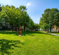 Greenery with benches and a walkway in front of the apartment buildings on Viestova Street in Myjava.