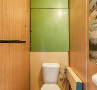 A toilet with a wooden decor floor in a 4-room apartment.