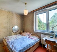 A bedroom with older furniture, wallpaper, and a window in a 4-room apartment.
