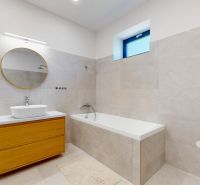 A bathroom in a family house with a bathtub and a mirror with a round frame.