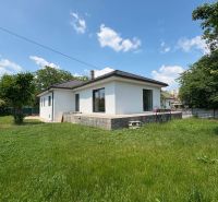 A family house in Komárom with a grassy garden and a terrace under the blue sky.