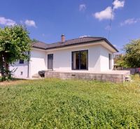 A family house in Komárom with a lawn and a tree on a sunny plot.