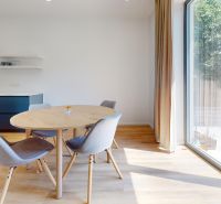 Interior of a family house with a dining table and a wooden-patterned floor.