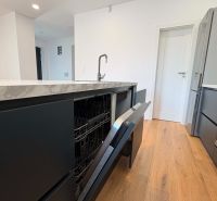 A kitchen in a family house with a dishwasher and a wooden decor floor.