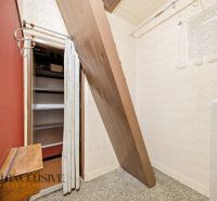 Storage space with a sloped roof in a family house with wallpapered walls.