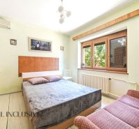 Bedroom with a large bed, sofa, and paintings in a family house.
