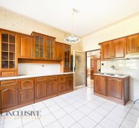 A kitchen in a family house with wooden cabinets and white tiles.