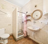 A bathroom in a family house with white tiles and a shower enclosure.