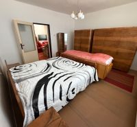 A bedroom in a family house with wooden wardrobes and a bed with a decorative cover.