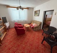A living room in a family house with a red carpet, a sofa, and armchairs.