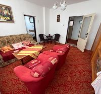 Living room in a family house with a patterned carpet, sofa, and armchairs.