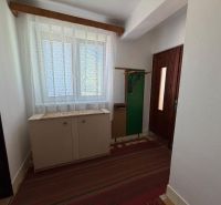 Entrance hallway in a family house with a shoe cabinet, coat rack, and patterned curtains.